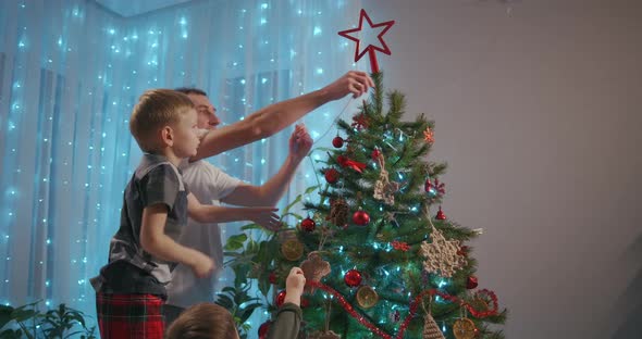 Father and Two Sons Decorate Christmas Tree Together