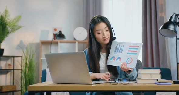Chinese Girl in Headset Explaining Charts During Video Conference with University's Teacher