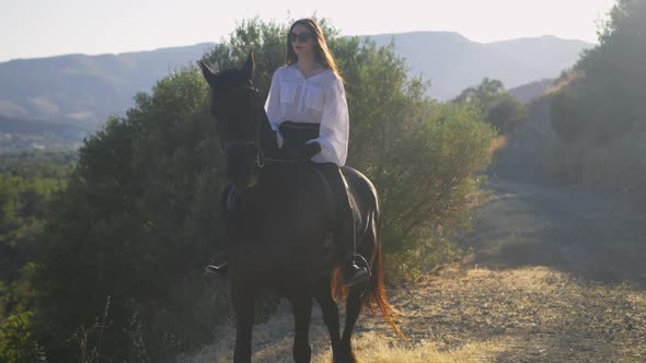 Wide Shot of Graceful Horse and Elegant Horsewoman Walking in Sunny Summer Mountains in Slow Motion