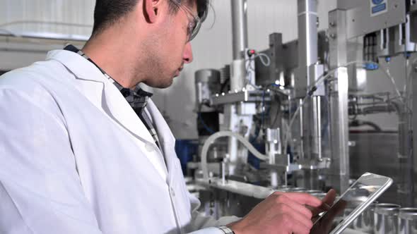 Factory Worker Inspecting Production Line on Beverage Factory with Computer Tablet