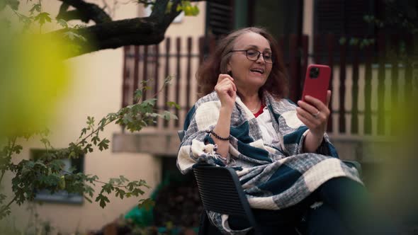 A Mature Adult Woman with Long Hair Taking a Video Call By Her Phone