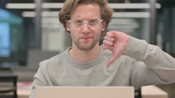 Portrait of Thumbs Down By Businessman with Laptop in Office