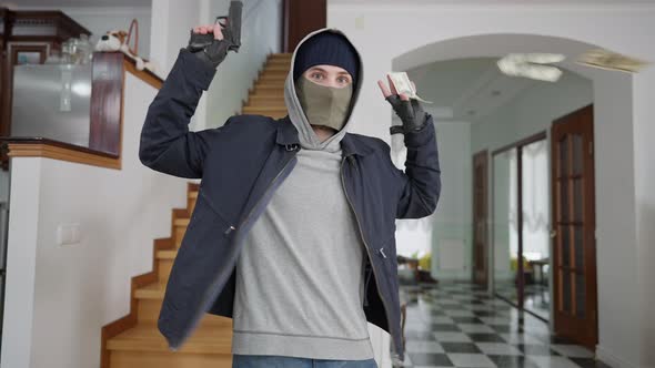 Middle Shot of Panicked Young Masked Thief Raising Hands and Looking at Camera