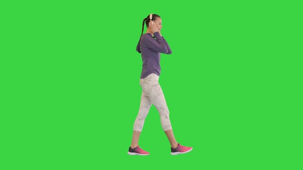 Young Athletic Girl on a Walk with Headphones on a Green Screen Chroma Key