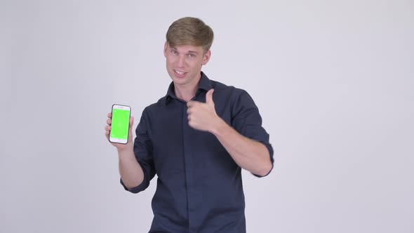 Happy Young Handsome Businessman Showing Phone and Giving Thumbs Up