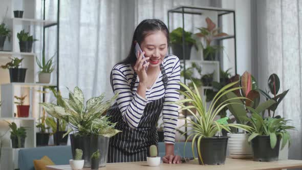 Asian Woman With Plants Talking On Phone At Home