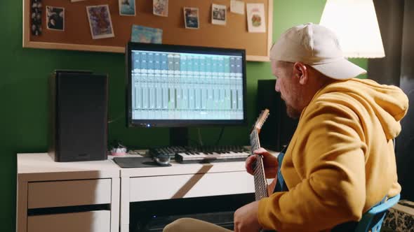Middleaged Man Playing Guitar and Creating Music Using Equalizer Program