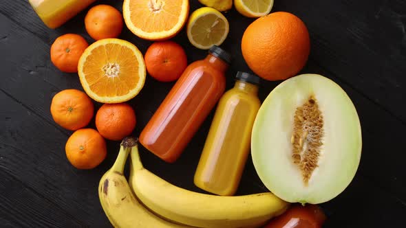 Mix of Orange and Yellow Colored Fruits and Juices on Black Wooden Background