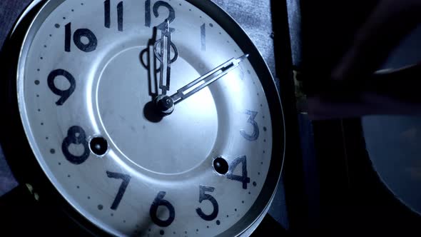 Close up of a  male hand is using the key to the ancient pendulum clock
