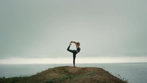 Fit Woman Standing One Leg Stretching on Hill