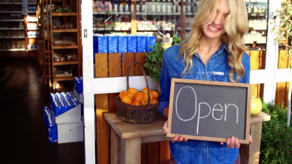 Smiling owner holding open signboard in supermarket