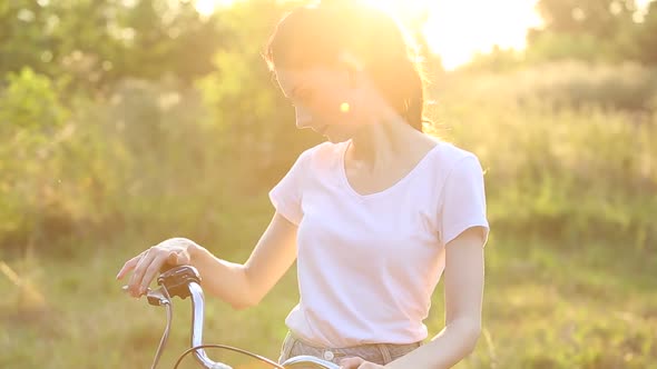 Woman checks hand brakes on bicycle before cycling in park at sunset