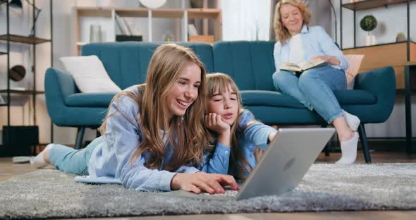 Two Sisters Younger and Eldest Lying on the Floor and Use Computer