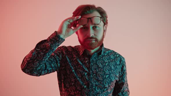 Young Handsome Bearded Caucasian Man Takes Off His Glasses Portrait Pink Gradient Background Studio