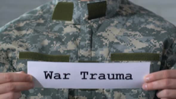 War Trauma Written on Paper in Hands of Male Soldier, PTSD Concept, Closeup