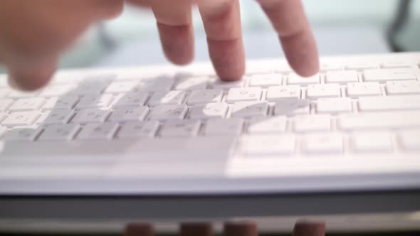 Close up on hand typing on white keyboard