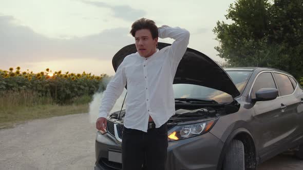 Nervous Man Stands Near His Broken Grey Car