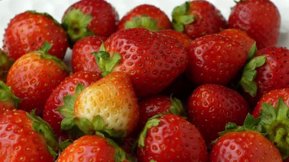 Beautiful ripe red strawberry rotates on a plate. Slow rotation of strawberries close-up top view