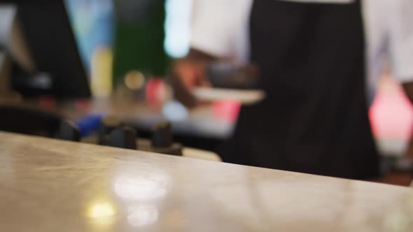 Midsection of african american male barista serving coffee in brown coffee cup