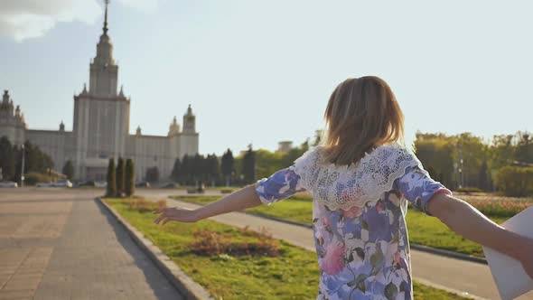 Young Young Blonde Girl Goes Happy on a Warm Summer Evening in the Park