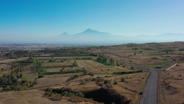 Aerial Drone Shot of Fields and Car Road on Background of Ararat Mountains