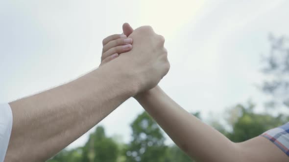 Unrecognizable Father and the Boy High Five and Shaking Hands Close-up Outdoors. Father and a Kid