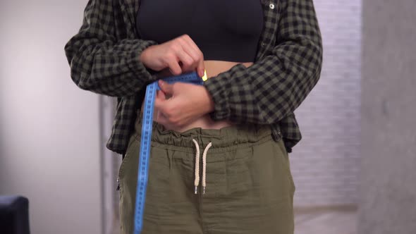 Overweight Woman Measuring Her Waist's Size with Tape Measure Loose Weight