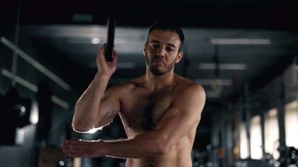 A Muscular Sportsman is Doing Exercise in the Gym