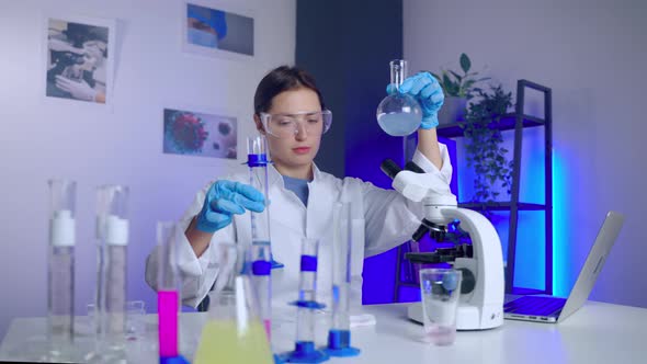 Woman Scientist is Experimenting in Chemical Laboratory Mixing Liquids in Test Tube