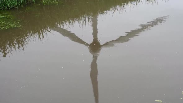 A single turning Wind Turbine reflected in a stream. East Frisia. Germany.