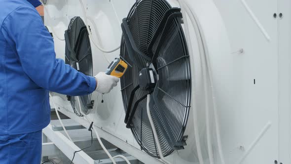 Technician uses a thermal imaging infrared thermometer to check the condensing