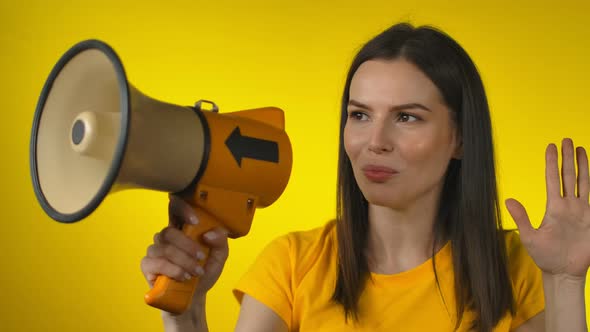 Shocked Darkhaired Young Woman in Casual Yellow Shirt Screaming in a Megaphone