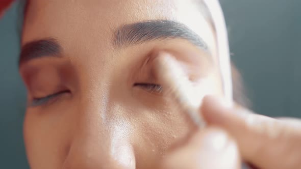 Close up of woman's eyes and make up artist putting a eye shadow with make up brush on her eyes