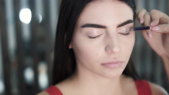 Makeup Artist Applies Eye Shadow To Eyes of Young Caucasian Brunette