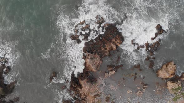 Aerial view of foaming sea waves crashing against rocky shore, coastline Crete Greece. Nature