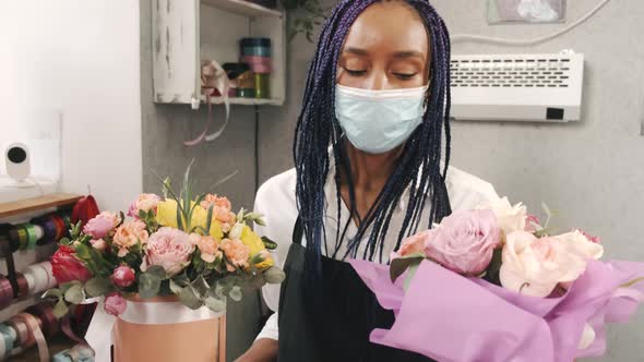 African American Woman Florist in Mask Holding Two Bunches of Flowers