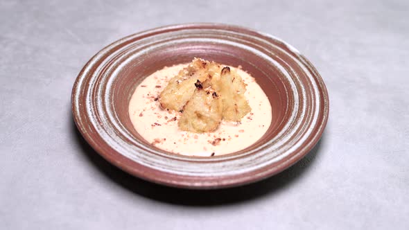 Woman's Hand Sprinkle Chopped Dill Baked Homemade Cauliflower in Plate with Gruyere Cheese Sauce