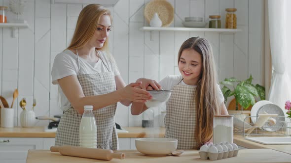 Adult Mother Blonde Woman and Little Daughter Teenager Girl Wear Aprons Learning to Cook Together