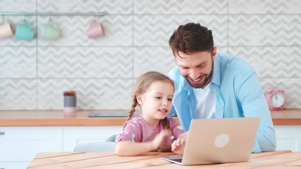 Smiling dad and little daughter talking on an online conference with mom using a laptop