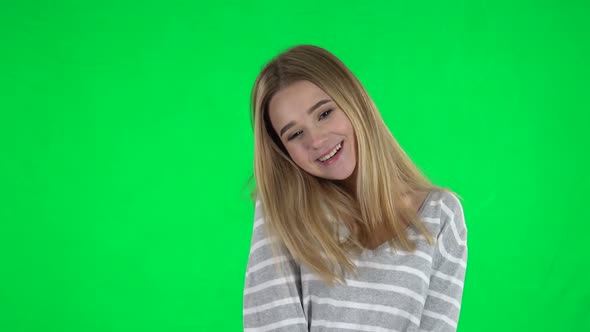 Portrait of Cute Blonde Girl with Long Hair Is Surprised and Very Happy on a Green Screen