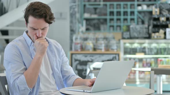 Young Man with Laptop Having Coughing