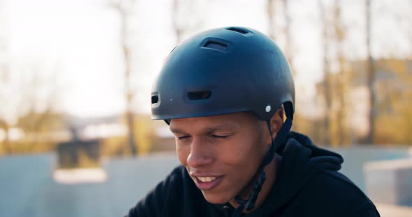 Closeup of Face of Handsome Boy with Dark Complexion Sitting on Bike Leaning Against Handlebars