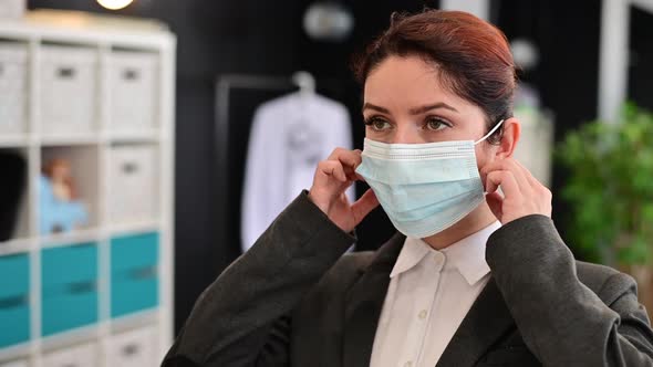 A Happy Female Office Worker in a Suit Takes Off Medical Mask