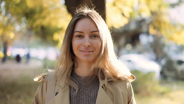 Portrait of Smiling Woman Outdoors in Lens Flares in Autumn