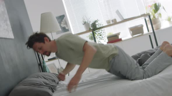 Sleepy Man Falling on Bed with Eyes Closed