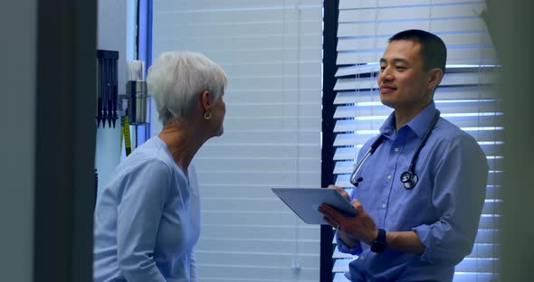 Young Asian male doctor and senior patient interacting with each other at clinic 4k