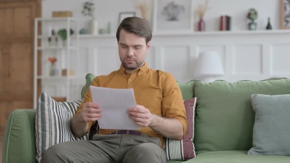 Young Man Reading Documents on Sofa