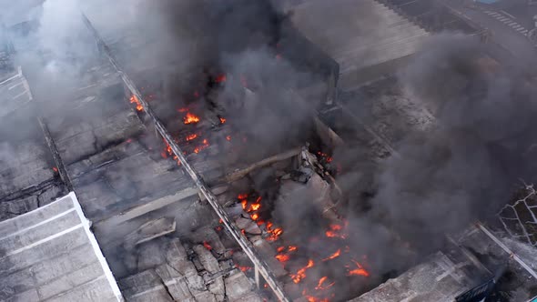 Aerial view overlooking a structure fire, a burning building, flames and dark smoke - Static, drone