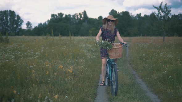 Tourist Girl Relaxing On Countryside Wildflower Field. Attractive Girl In Sunglasses And Dress.