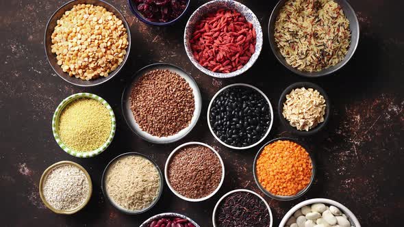 Various Superfoods in Smal Bowls on Dark Rusty Background